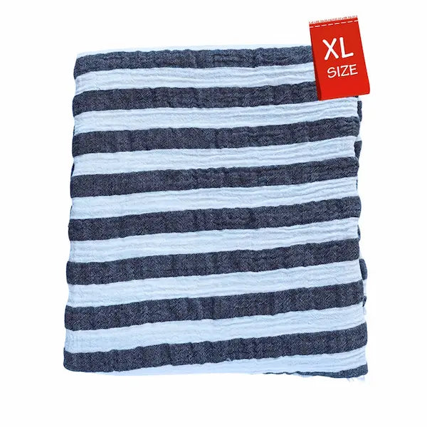 Close-up detail of breathable muslin texture of black and white striped Summer Forever cotton beach towel with an XL size tag on a white background